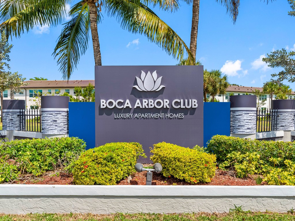 A sign for Boca Arbor Club in front of some trees.